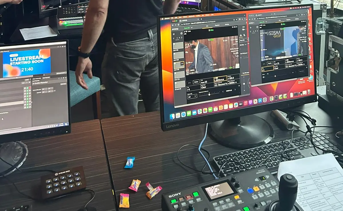 A live production desk with remote camera control software on screen, a “Livestream starting soon” holding slide and a hardware camera controller