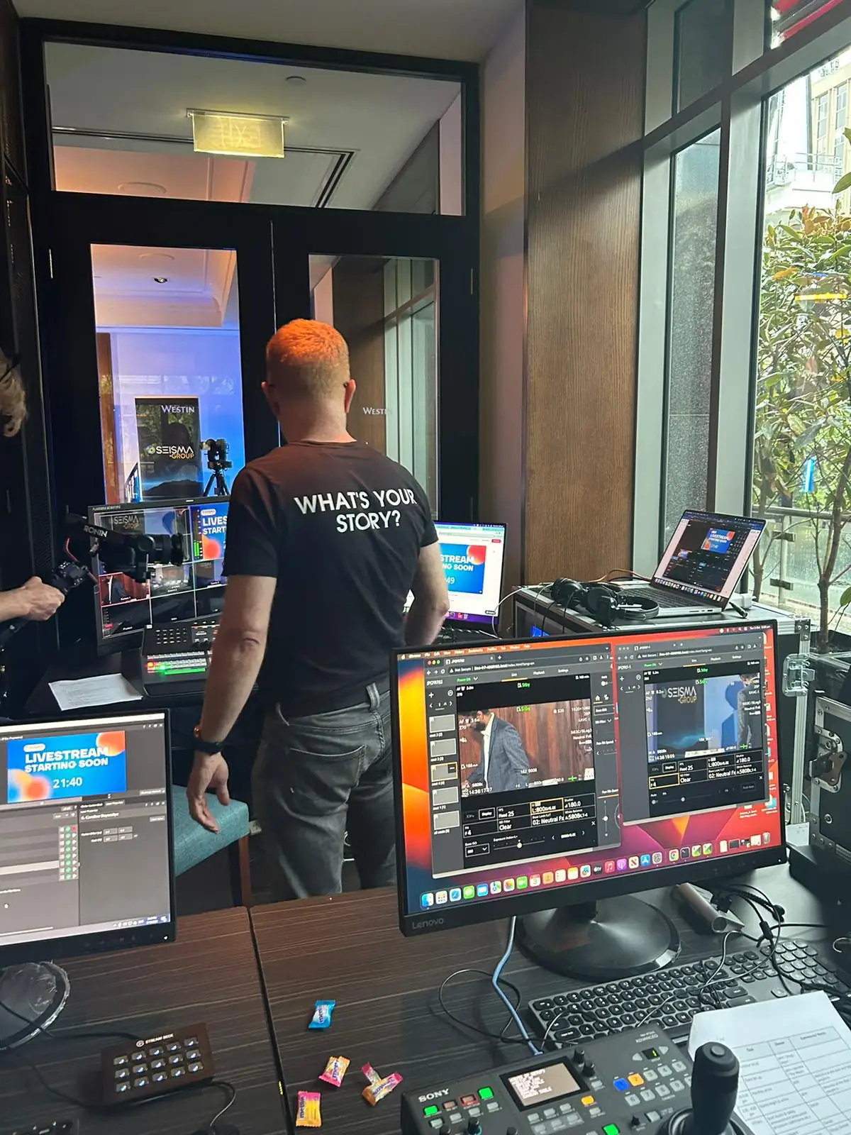 JPC crew at the live production desk for a hotel ballroom event, with a vision switcher, camera controls and a multiview showing the programme and a “Livestream starting soon” screen